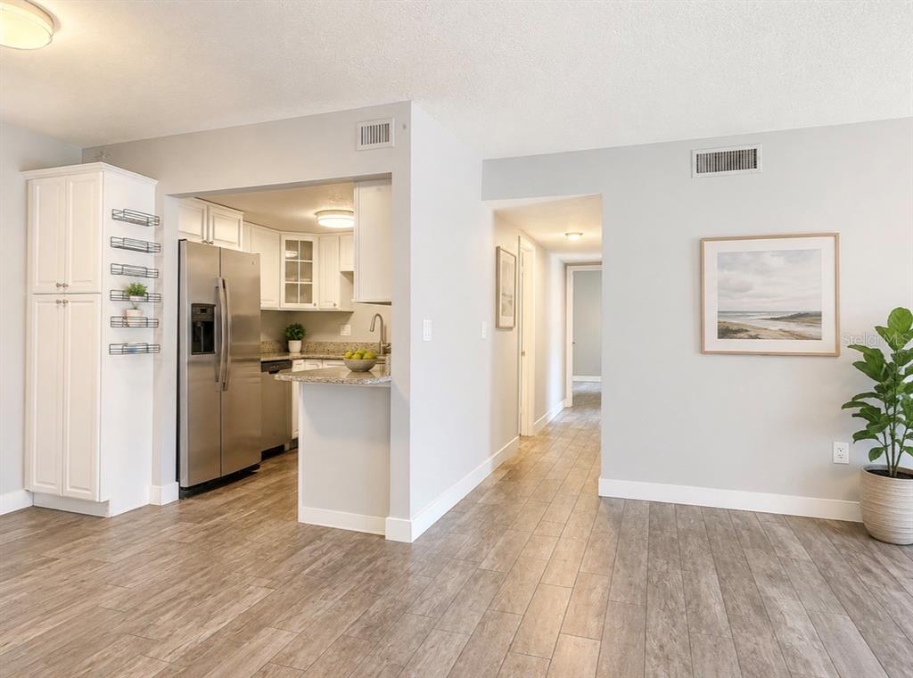 A kitchen with stainless steel appliances and a breakfast bar opens to a hallway — 912 LAKE DESTINY ROAD UNIT D, ALTAMONTE SPRINGS, FL