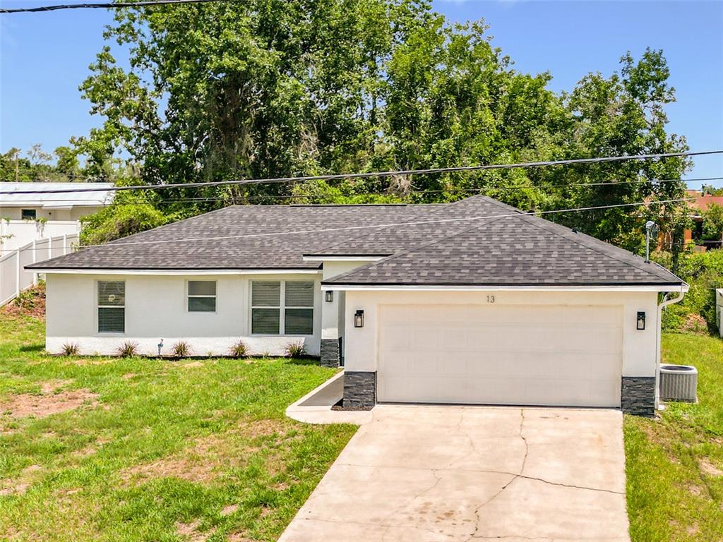 A single-story white house with a dark shingled roof and a two-car garage — 13 JUNIPER PASS RADIAL, OCALA, FL