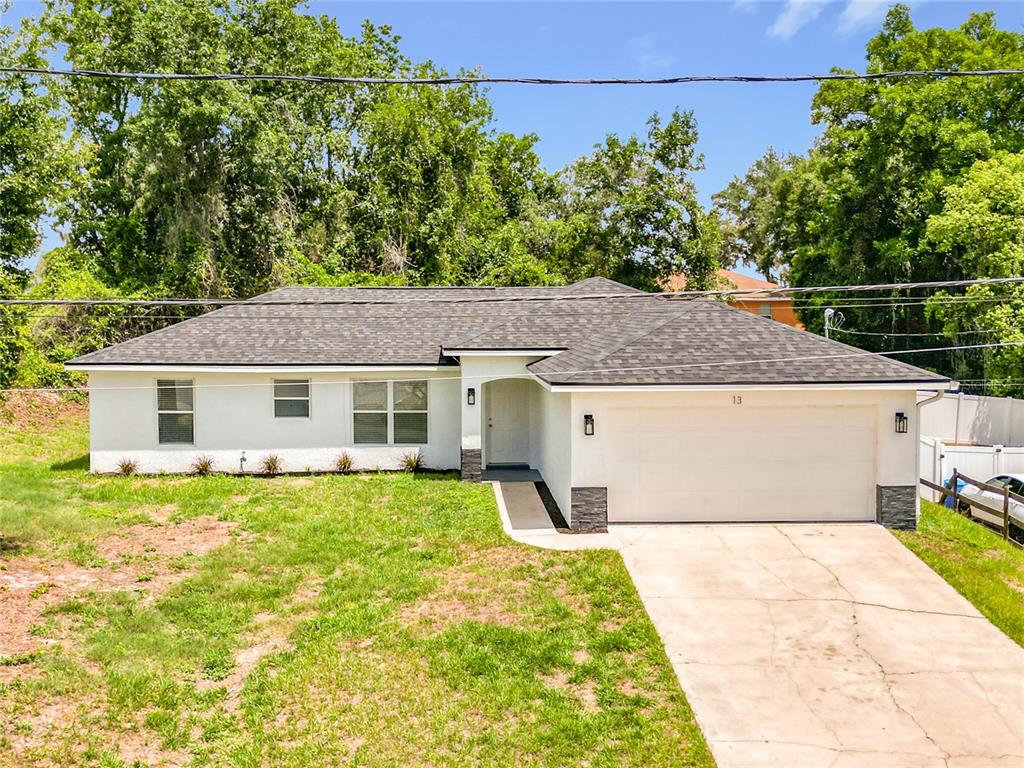 An aerial view shows a single-story white house with a dark roof and driveway — 13 JUNIPER PASS RADIAL, OCALA, FL