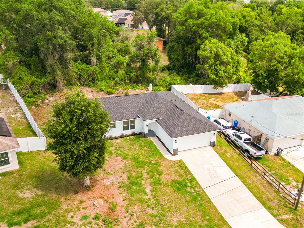 An aerial view shows a white house with a dark shingled roof and a driveway — 13 JUNIPER PASS RADIAL, OCALA, FL
