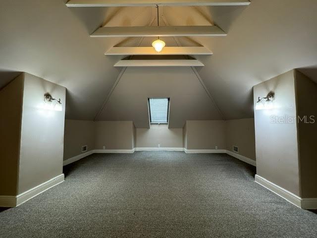 An attic room with carpeted floors, sloped ceilings, exposed beams, and wall-mounted light fixtures — 201 E VOORHIS AVENUE, DELAND, FL