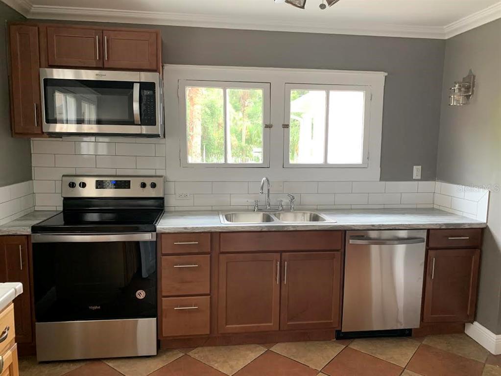 A kitchen features wood cabinets, stainless steel appliances, a white subway tile backsplash, and windows — 201 E VOORHIS AVENUE, DELAND, FL