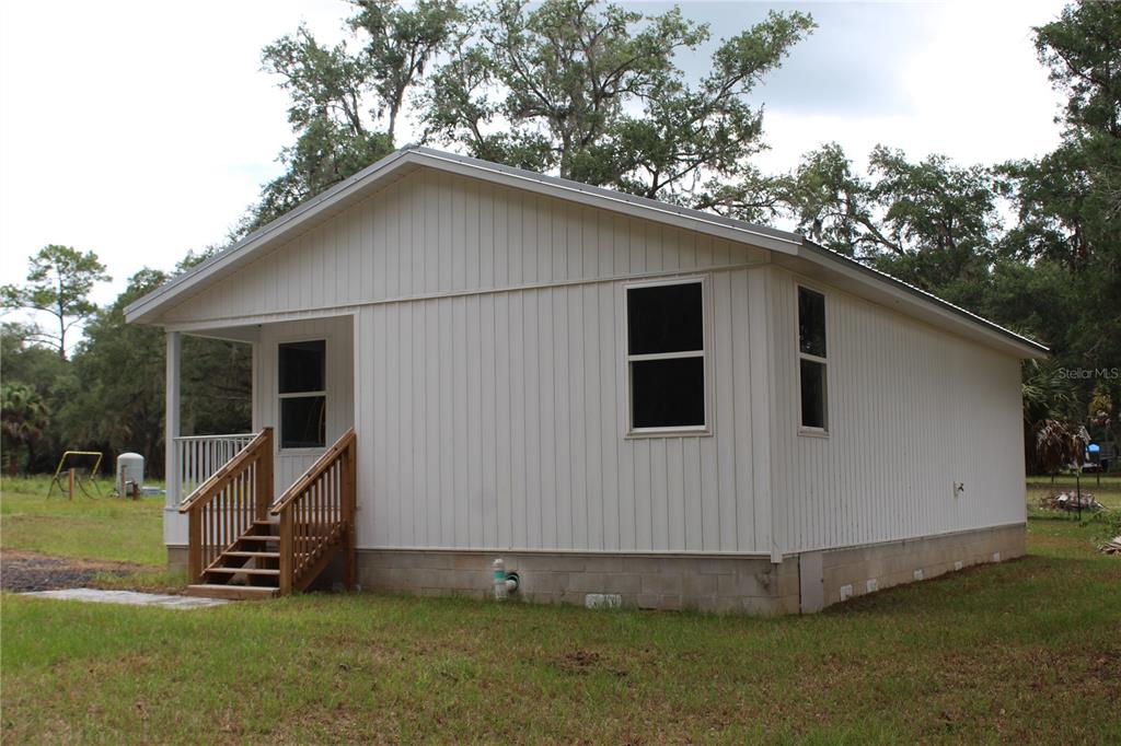 A white, single-story house with vertical siding, a front porch, and a concrete block foundation — 11629 NE 145TH PLACE, FORT MC COY, FL