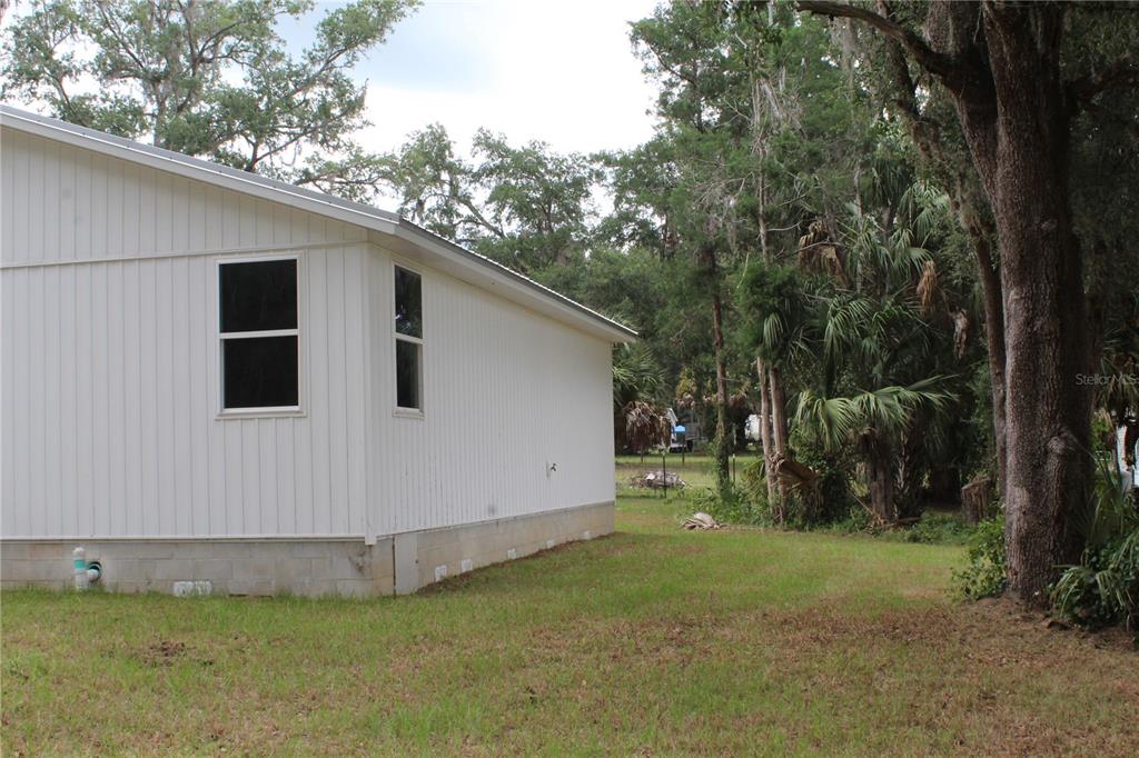 The exterior side of a white house with vertical siding and a concrete block foundation — 11629 NE 145TH PLACE, FORT MC COY, FL