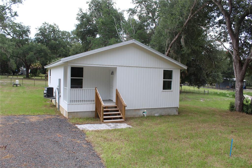 A white, single-story house with a front porch and wooden stairs sits on a grassy lot — 11629 NE 145TH PLACE, FORT MC COY, FL