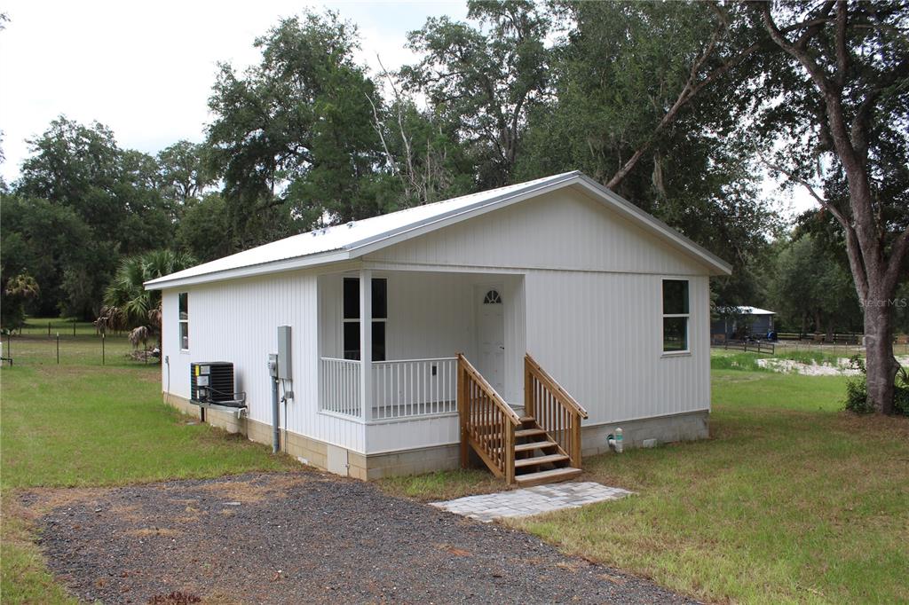 A white, single-story house with a metal roof, a front porch, and wooden stairs — 11629 NE 145TH PLACE, FORT MC COY, FL