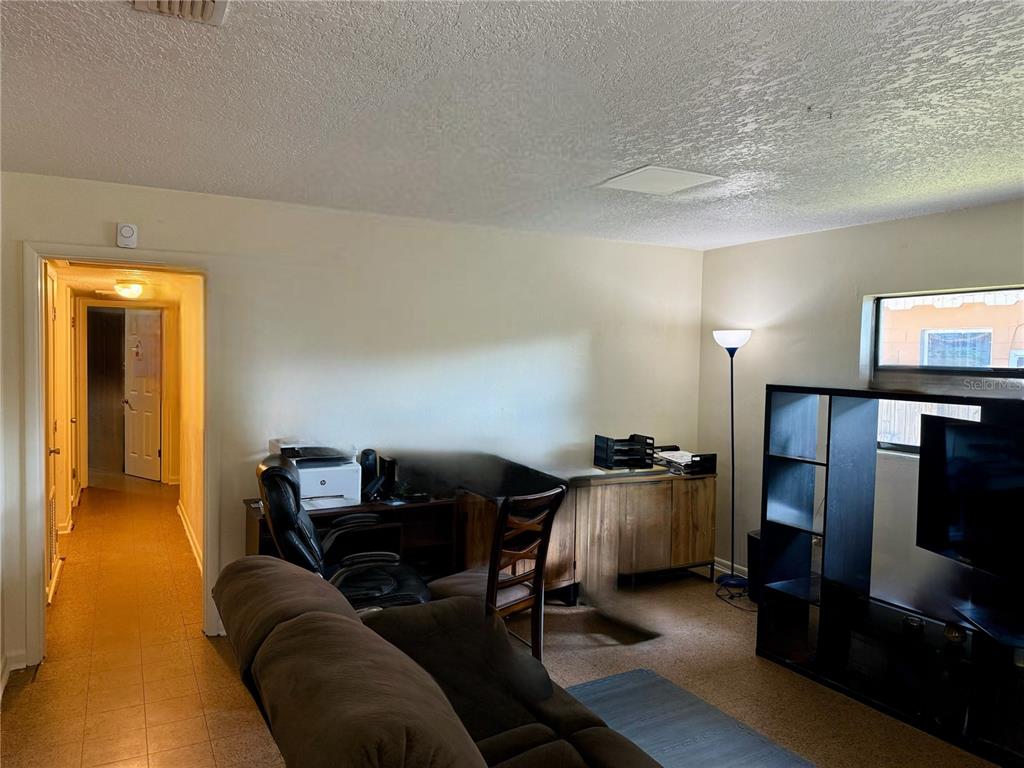 A living room features a brown sofa, a desk area, and a black shelving unit — 6233 BALBOA DRIVE, ORLANDO, FL