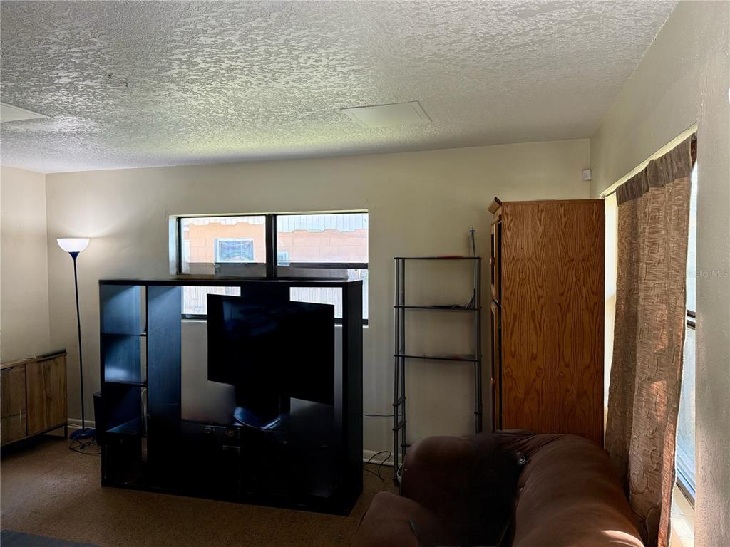 A living room features a black media console, a brown sofa, and a tall wooden cabinet — 6233 BALBOA DRIVE, ORLANDO, FL