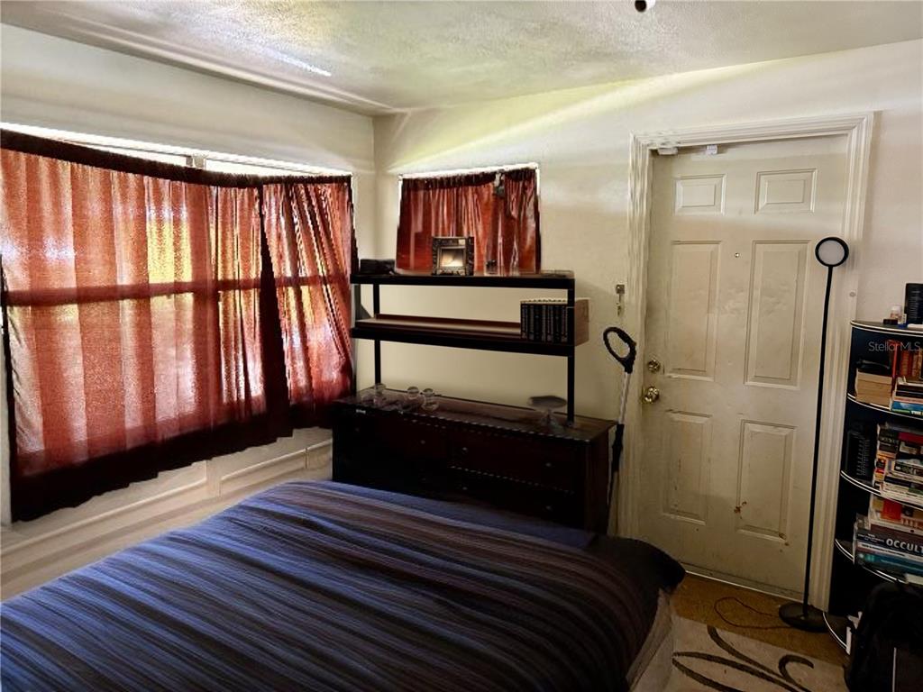 A bedroom features a bed, a dark wood dresser with shelving, and sheer brown curtains — 6233 BALBOA DRIVE, ORLANDO, FL