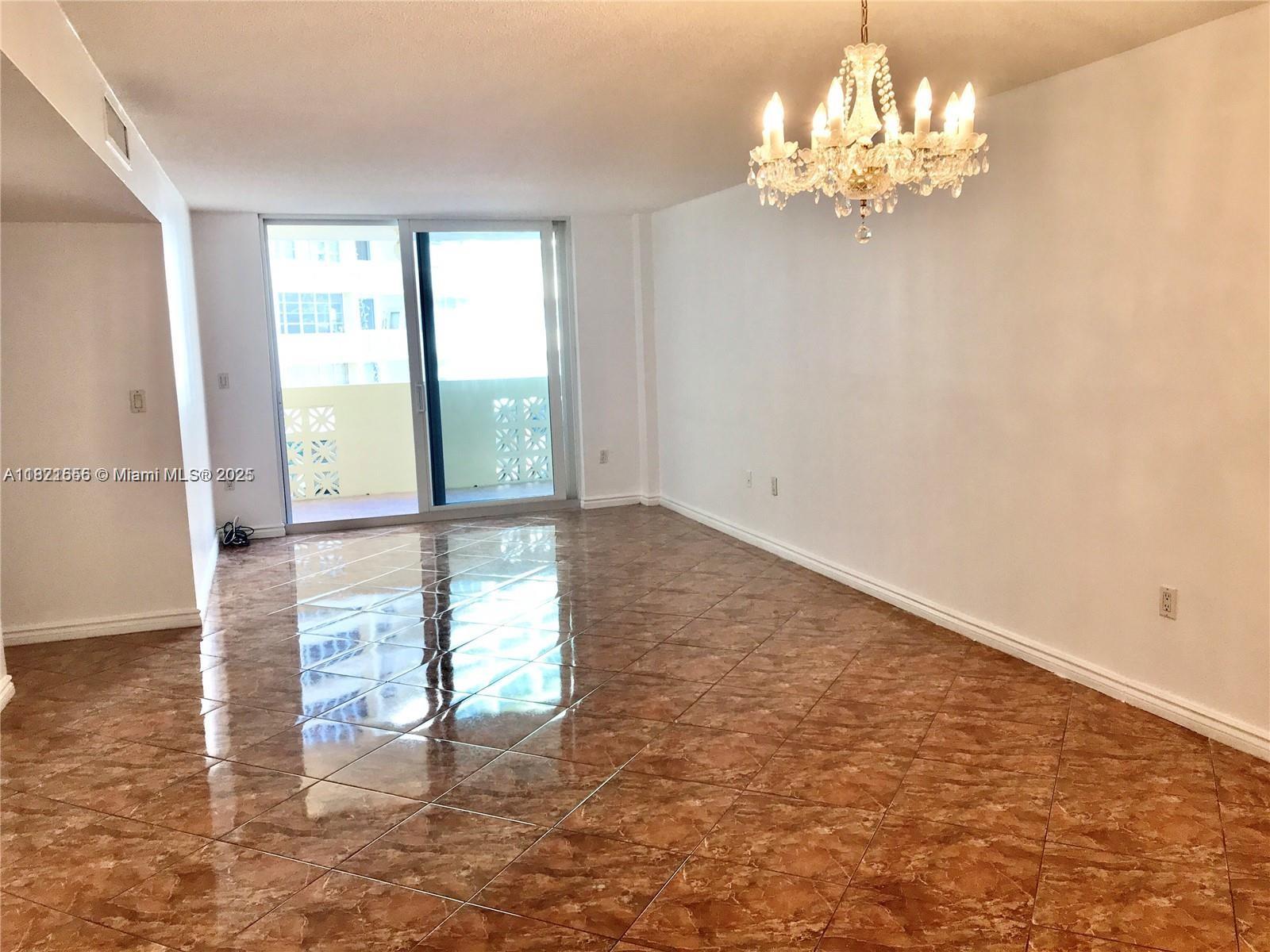 A living room with brown tile flooring, white walls, and a crystal chandelier — 1833 S Ocean Dr # 305, Hallandale Beach FL 33009, HALLANDALE BEACH, FL