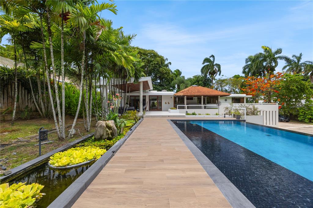 A modern house with a swimming pool and a long wooden walkway beside a pond — 1841 BEGONIA ST, SANTA MARIA, SAN JUAN, PR