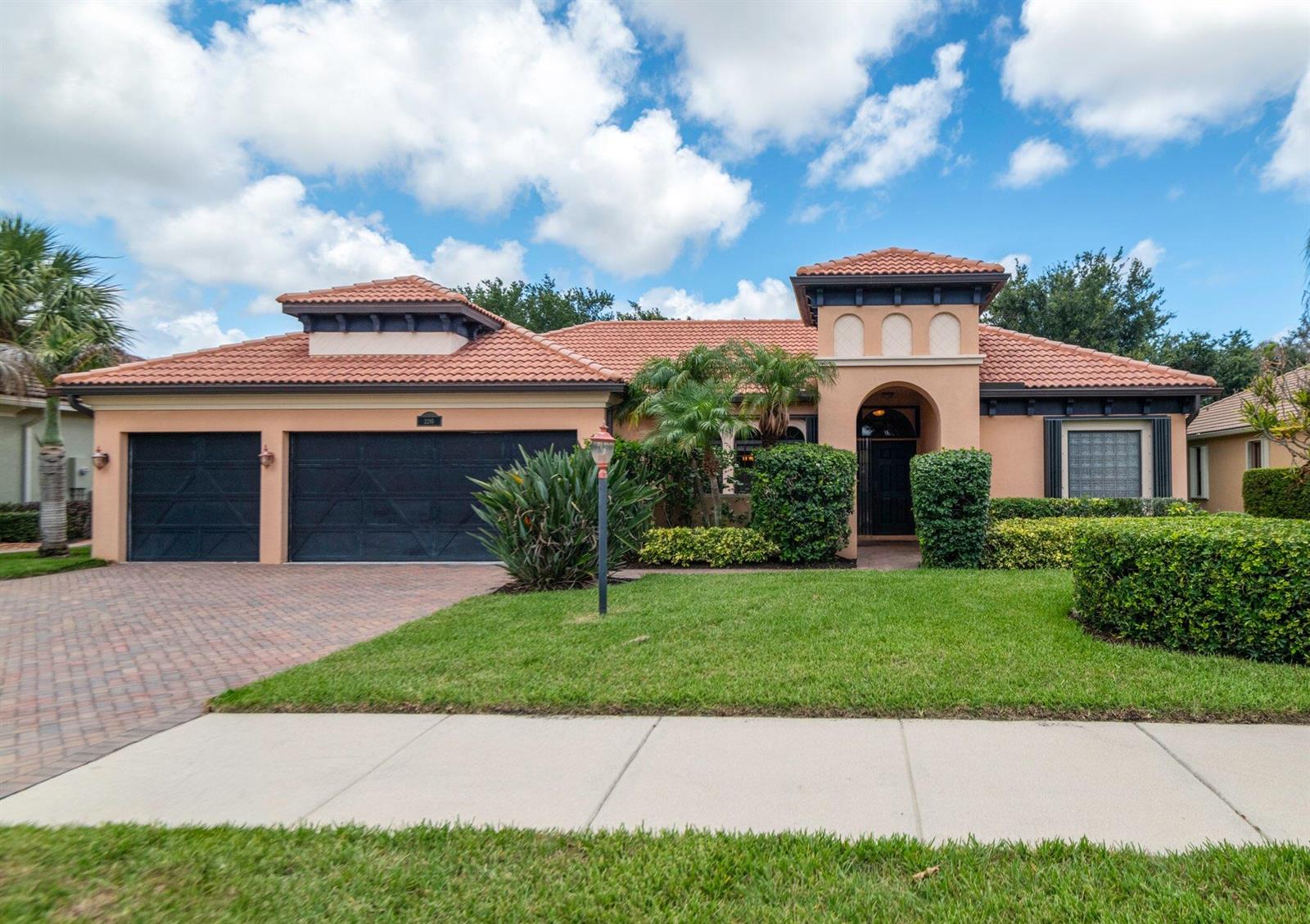 A single-story house with a terracotta tile roof, stucco exterior, and a two-car garage — 2295 NW Diamond Creek Way, Jensen Beach FL 34957, JENSEN BEACH, FL