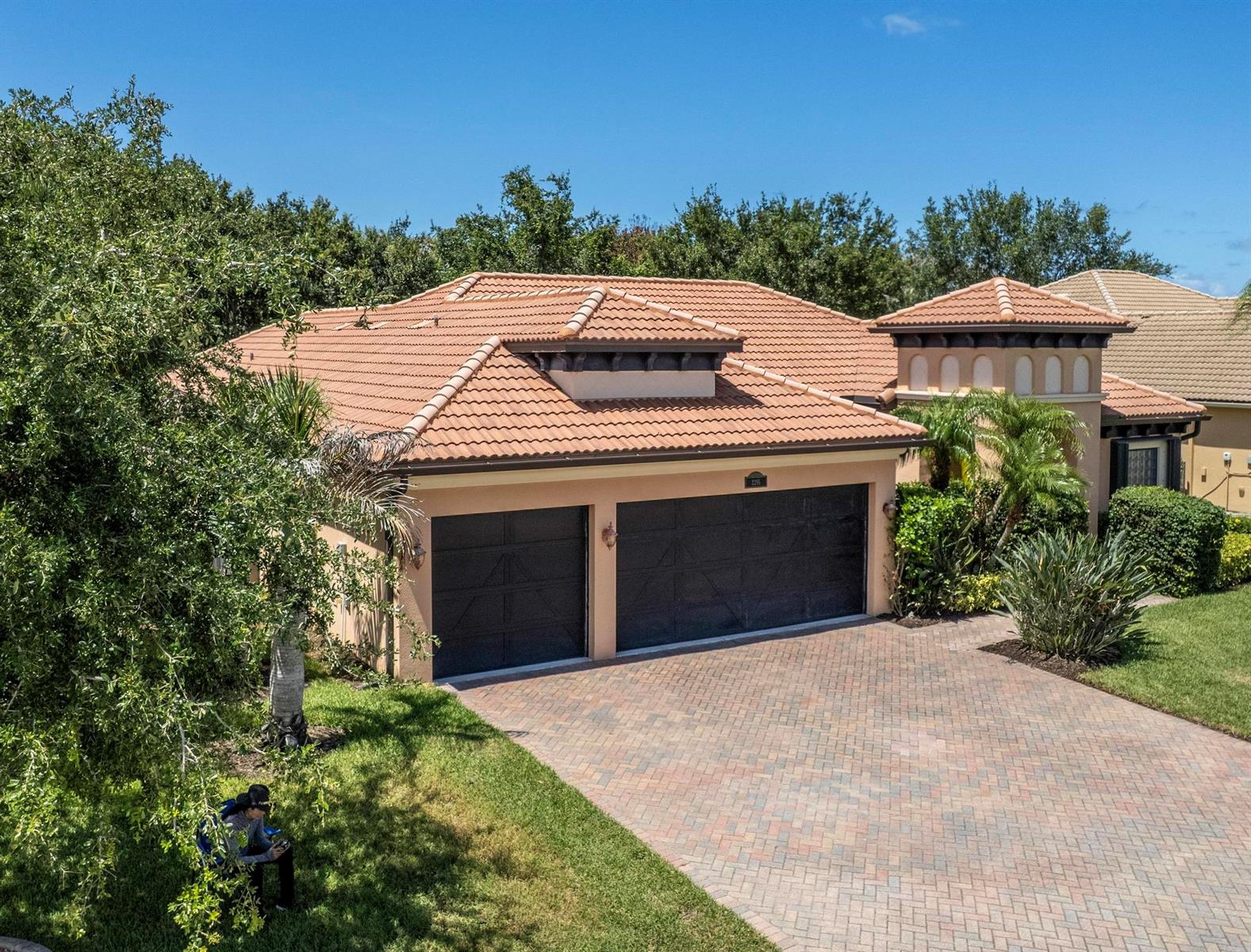An exterior view of a house with a tile roof, two garage doors, and a driveway — 2295 NW Diamond Creek Way, Jensen Beach FL 34957, JENSEN BEACH, FL