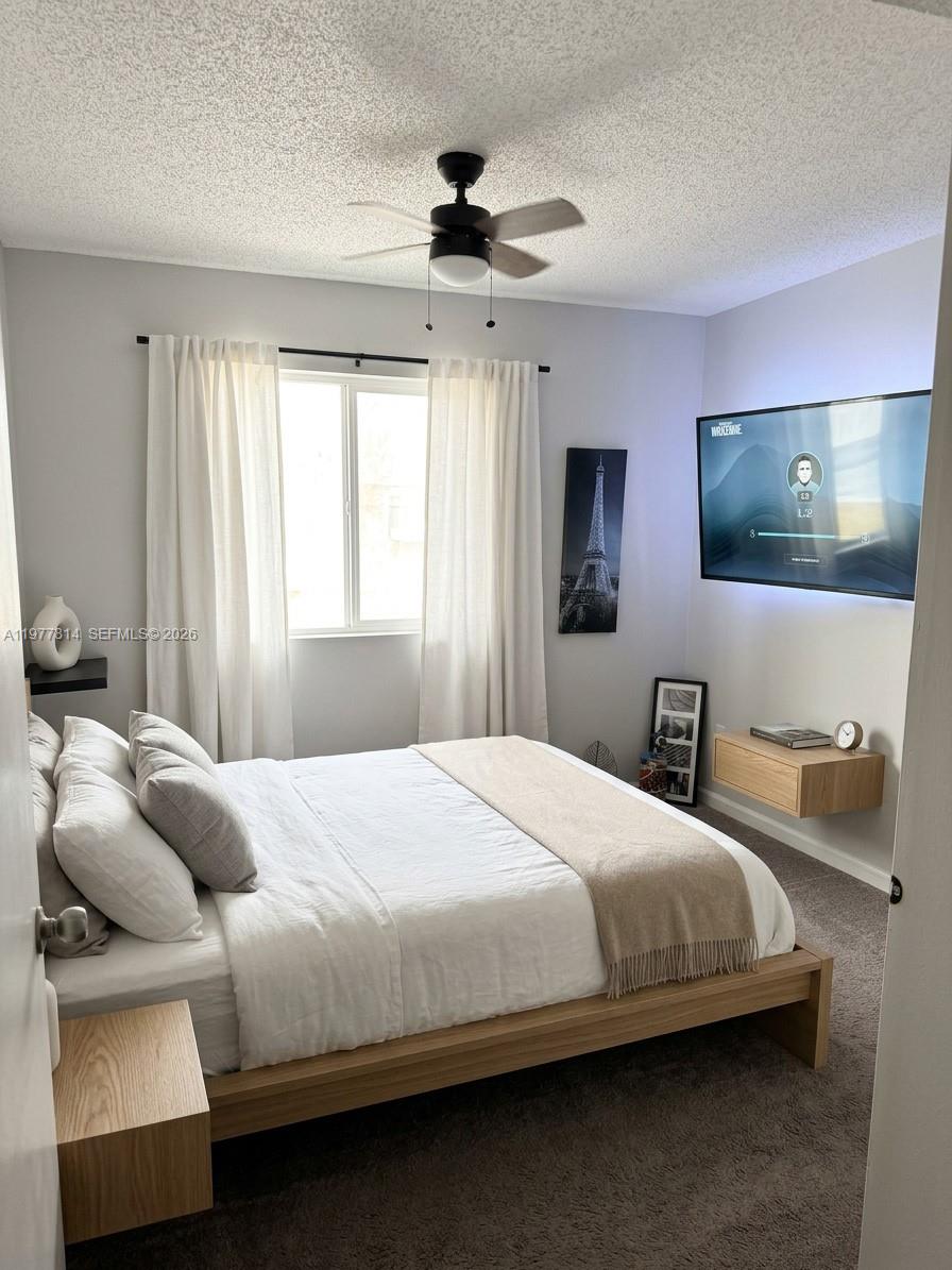 A bedroom features a platform bed, a wall-mounted television, and a ceiling fan — 440 S Park Rd # 102, Hollywood FL 33021, HOLLYWOOD, FL