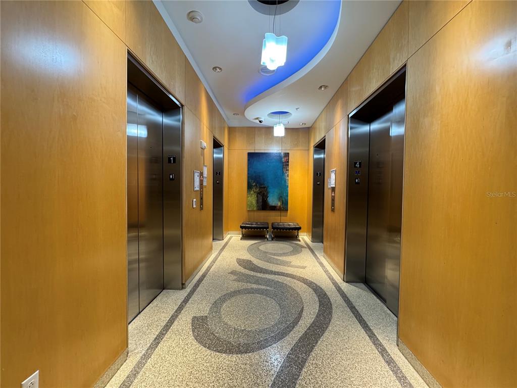 An elevator lobby features wood-paneled walls, a patterned floor, and two modern light fixtures — 150 E ROBINSON STREET UNIT 29B, ORLANDO, FL