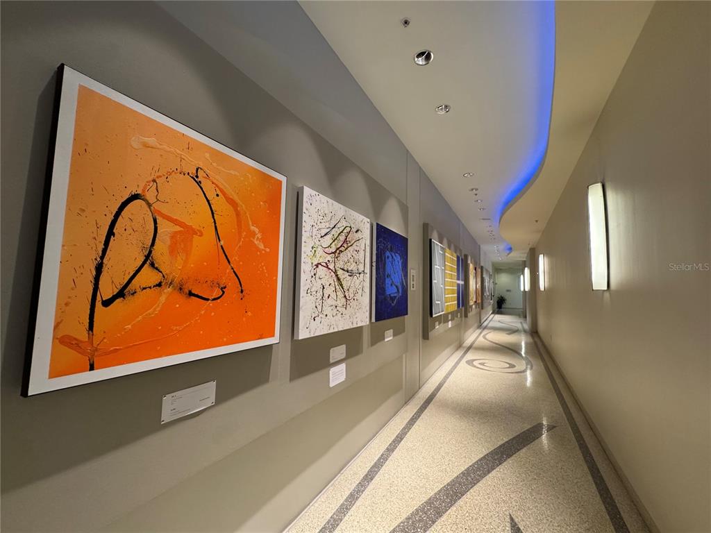 A hallway features a series of abstract paintings on the wall and a patterned floor — 150 E ROBINSON STREET UNIT 29B, ORLANDO, FL