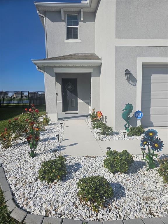 A gray two-story house features a front walkway, white rock landscaping, and decorative garden accents — 10116 CHARLOTTE DRIVE, PARRISH, FL