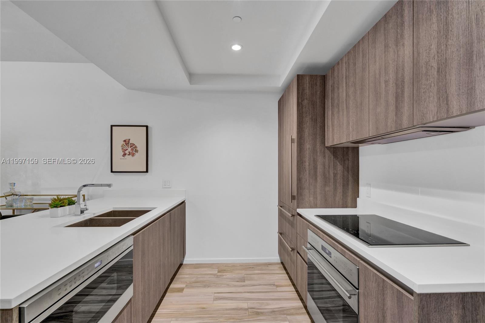 A modern kitchen features wood-grain cabinetry, white countertops, and stainless steel appliances — 801 S Miami Ave # 1106, Miami FL 33130, MIAMI, FL