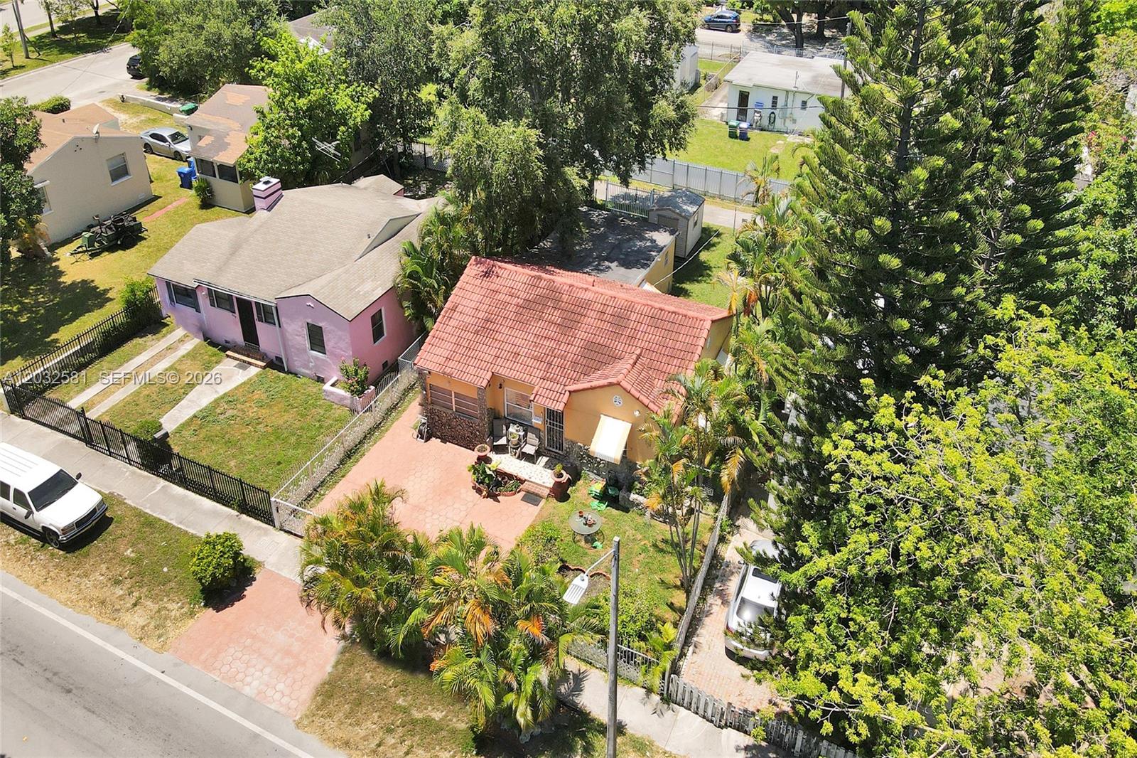 An aerial view shows two adjacent houses with tiled roofs, paved driveways, and surrounding trees — 555 NW 46th St, Miami FL 33127, MIAMI, FL