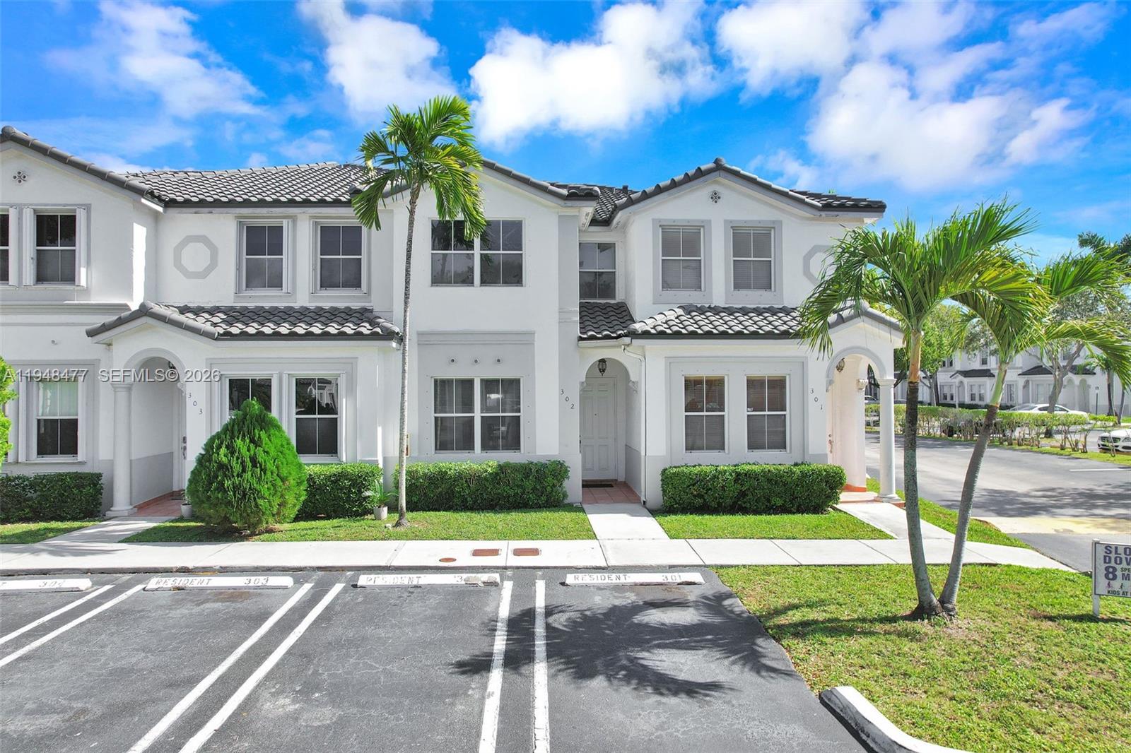 A two-story white townhouse with a tiled roof and designated parking spaces in front — 5420 NW 107 AVE # 302, Doral FL 33178, DORAL, FL