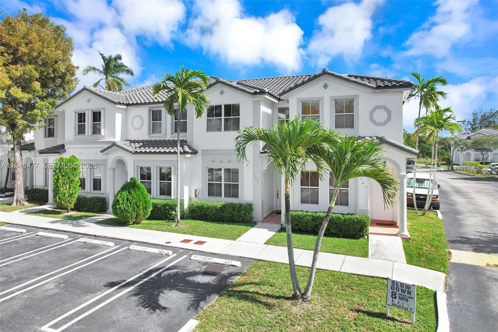A two-story white townhouse with a tiled roof, palm trees, and a parking lot — 5420 NW 107 AVE # 302, Doral FL 33178, DORAL, FL