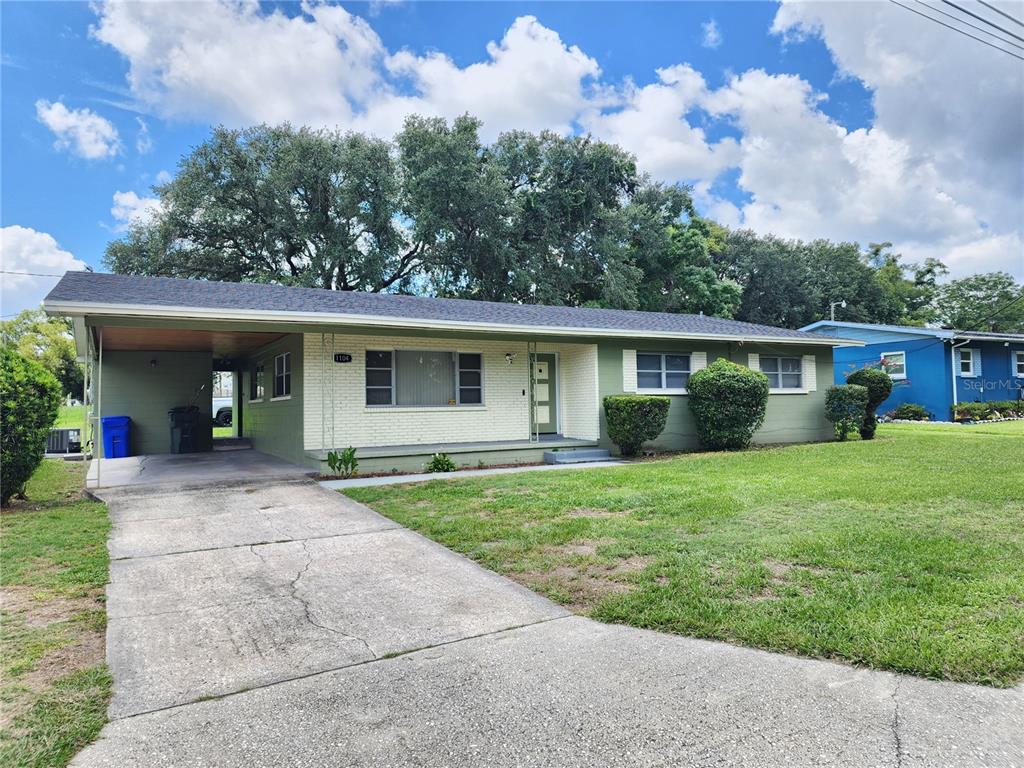 A single-story house with a green and white exterior, a carport, and a concrete driveway — 1104 W 14TH STREET, LAKELAND, FL