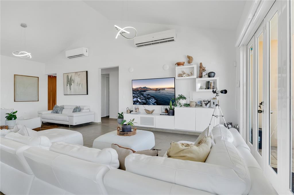 A bright, white living room features a sectional sofa, a wall-mounted television, and vaulted ceilings — Palmas del Mar THE VIEWS #22, HUMACAO, PR