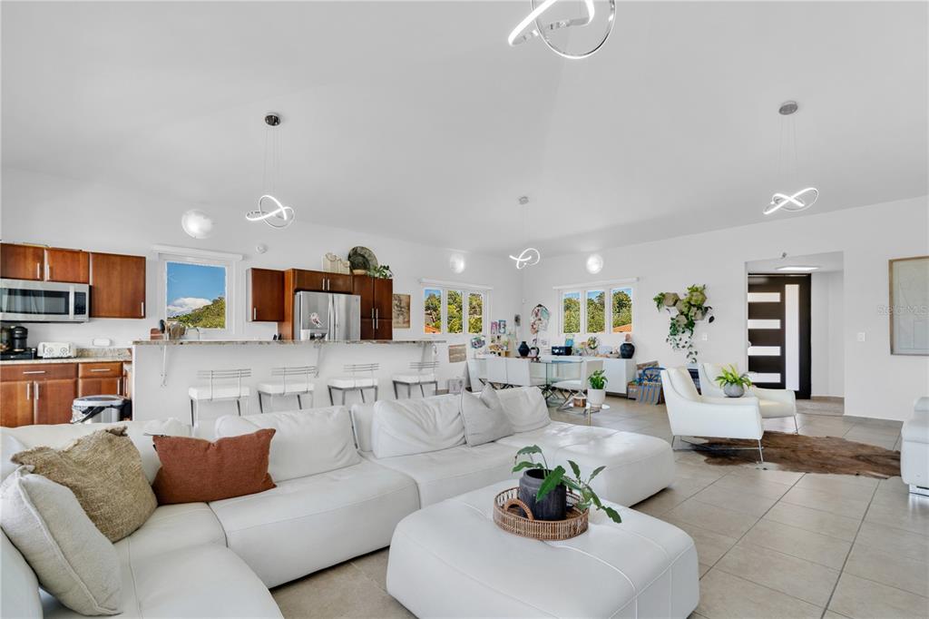 An open-concept living room and kitchen feature white leather furniture, tile floors, and pendant lighting — Palmas del Mar THE VIEWS #22, HUMACAO, PR