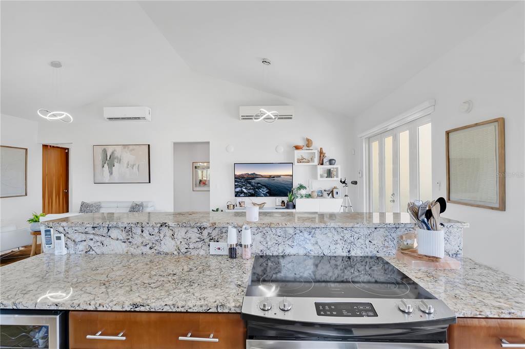 A kitchen island with a granite countertop overlooks a living area with a television — Palmas del Mar THE VIEWS #22, HUMACAO, PR