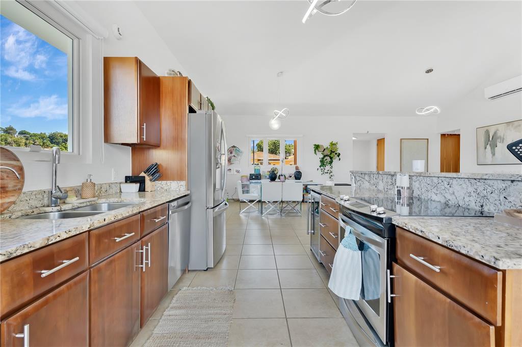 A kitchen with wood cabinets, granite countertops, and stainless steel appliances leads to a dining area — Palmas del Mar THE VIEWS #22, HUMACAO, PR