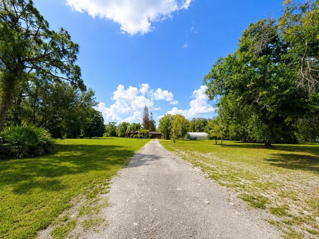 A gravel driveway leads toward a house and a metal outbuilding on a grassy lot — 5280 HAYWOOD RUFFIN ROAD, ST CLOUD, FL