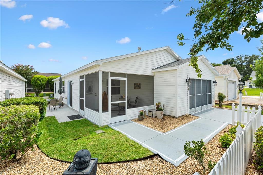 A white house with a screened-in porch, a concrete patio, and a white picket fence — 2752 CRAVEN WAY, THE VILLAGES, FL