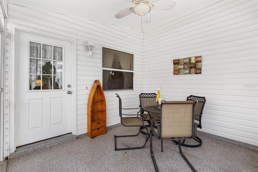 A covered patio features white vinyl siding, a ceiling fan, and a small dining set — 2752 CRAVEN WAY, THE VILLAGES, FL