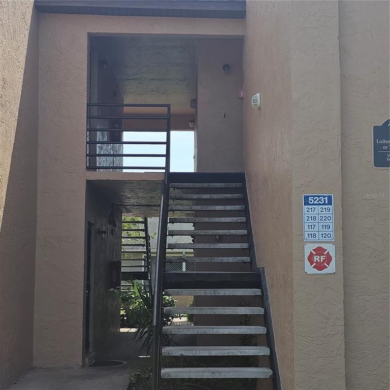 An exterior view of an apartment building staircase leading to upper-level units — 5231 VIA HACIENDA CIRCLE UNIT 117, ORLANDO, FL