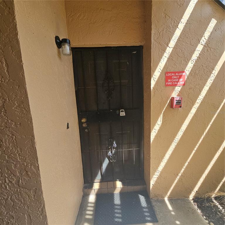 A black metal security door is installed at the entrance of a stucco building — 5231 VIA HACIENDA CIRCLE UNIT 117, ORLANDO, FL