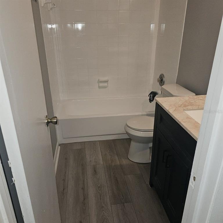 A bathroom features a white tub, a toilet, and a dark vanity with a stone countertop — 5231 VIA HACIENDA CIRCLE UNIT 117, ORLANDO, FL