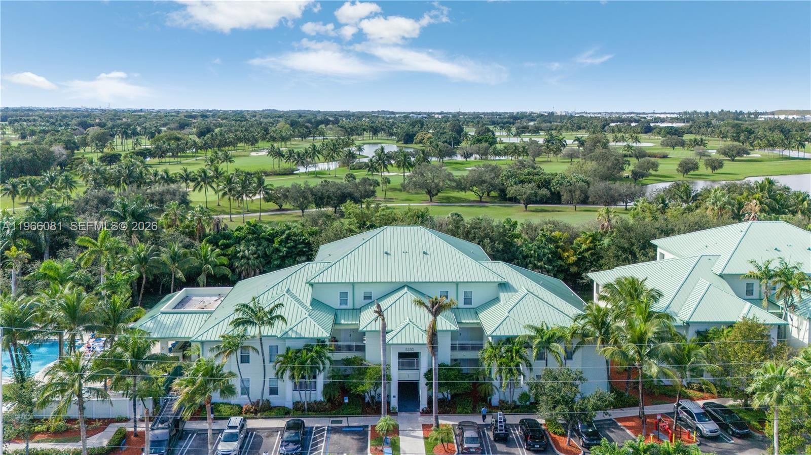 An aerial view shows a multi-story apartment building with a green metal roof — 5300 NW 87th Ave # 108, Doral FL 33178, DORAL, FL