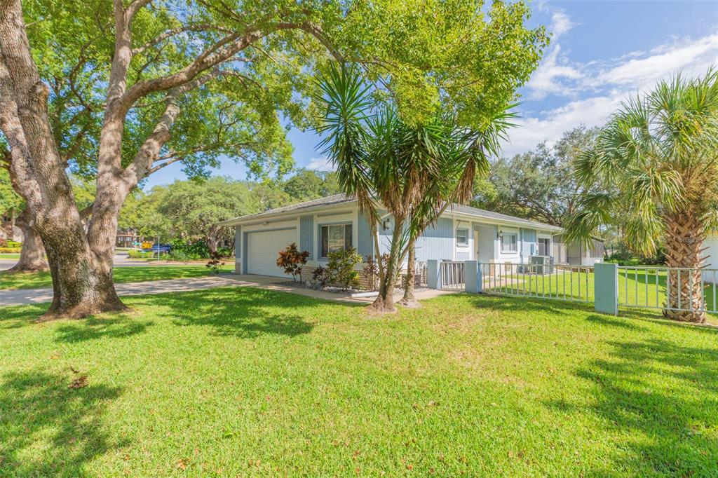 A single-story house with light blue siding, a garage, and a large front lawn — 13016 CLUB DRIVE, HUDSON, FL