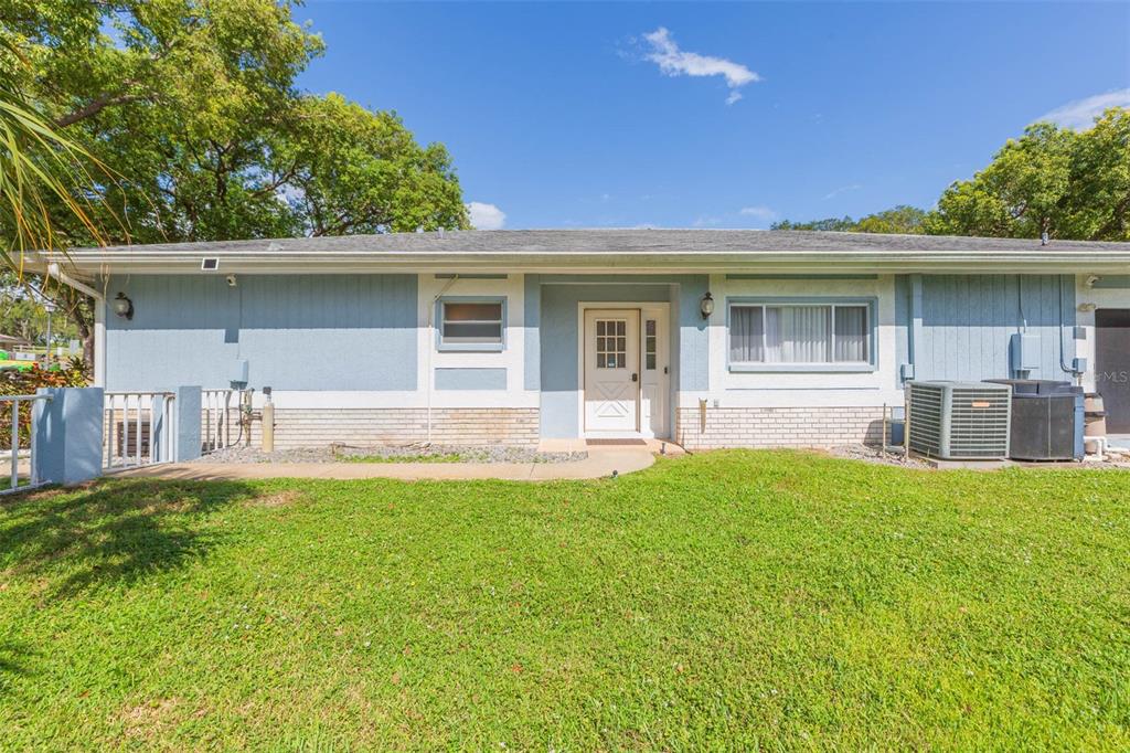A single-story house with blue siding, a white front door, and a grassy front yard — 13016 CLUB DRIVE, HUDSON, FL