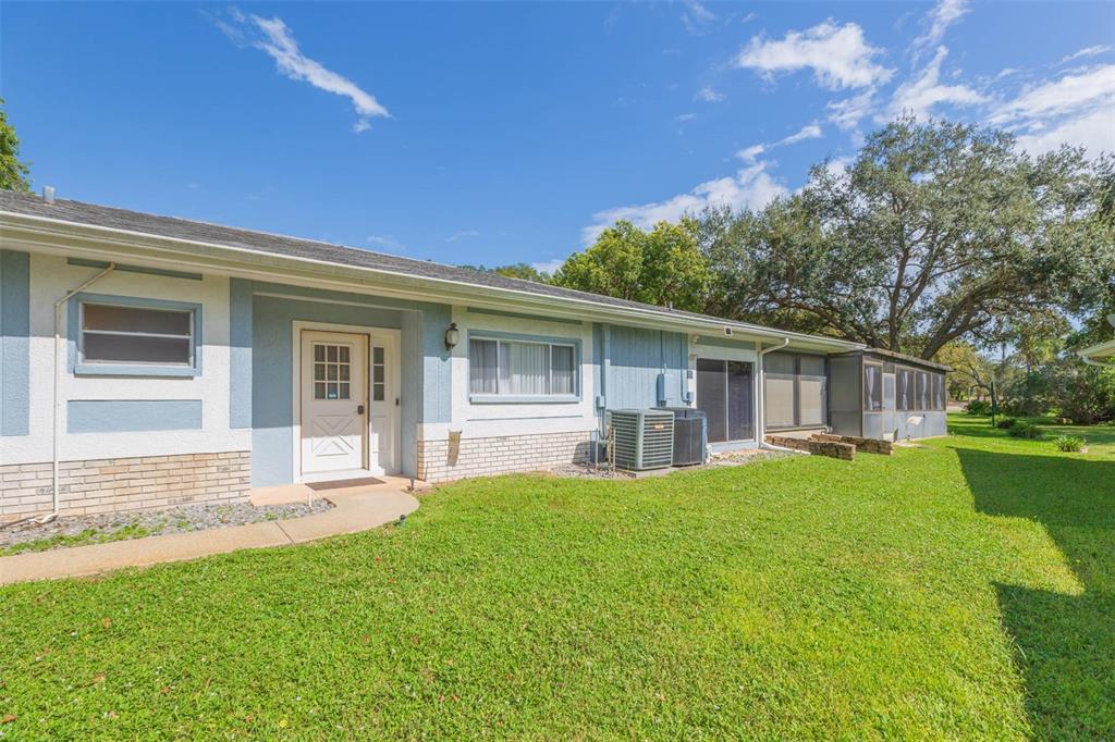 A single-story house exterior with blue siding, a white front door, and a grassy lawn — 13016 CLUB DRIVE, HUDSON, FL
