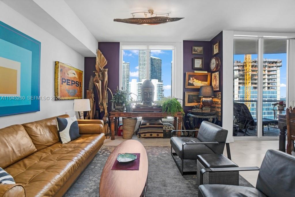 A living room features a leather sofa, dark chairs, a Buddha statue, and city views — 601 NE 27th St # 1505, Miami FL 33137, MIAMI, FL