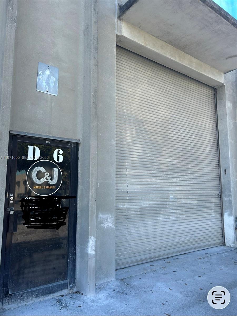 The exterior of a commercial building features a metal roll-up door and a glass entrance door — 5301 NW 15 ST, Margate FL 33063, MARGATE, FL