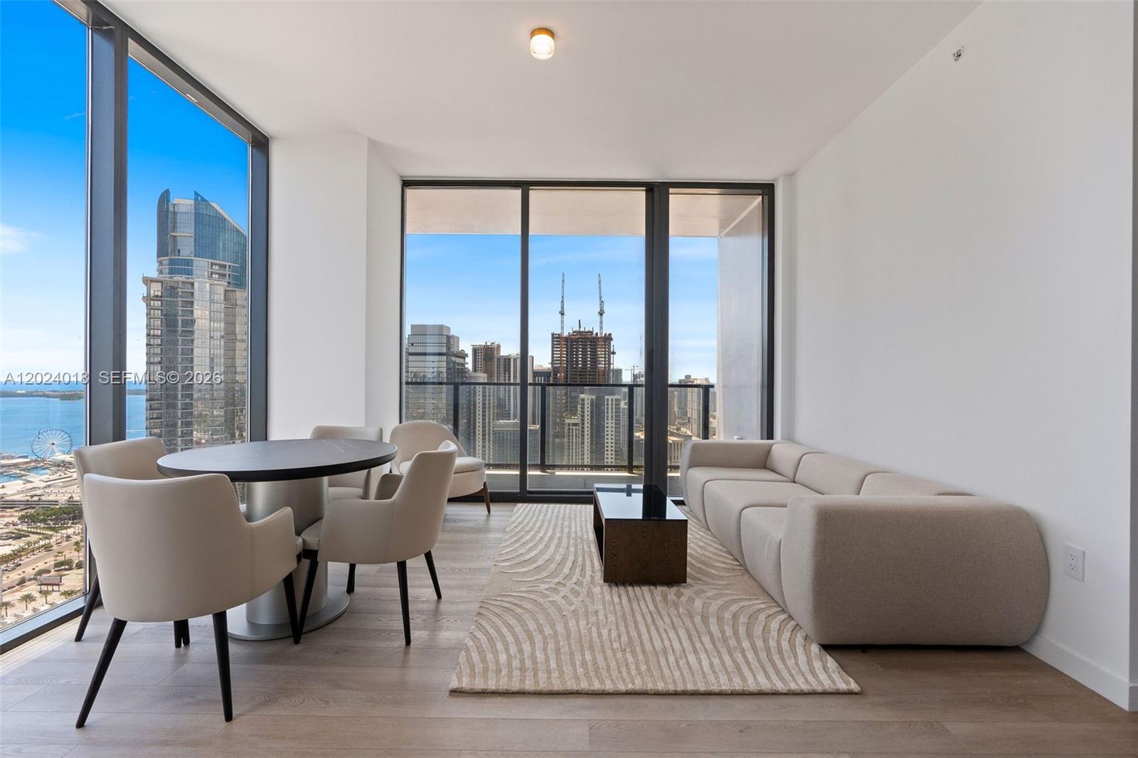 A modern living and dining area features floor-to-ceiling windows with views of a city skyline — 20 NE 11th 20 NE 11TH ST # 4504, Miami FL 33132, MIAMI, FL