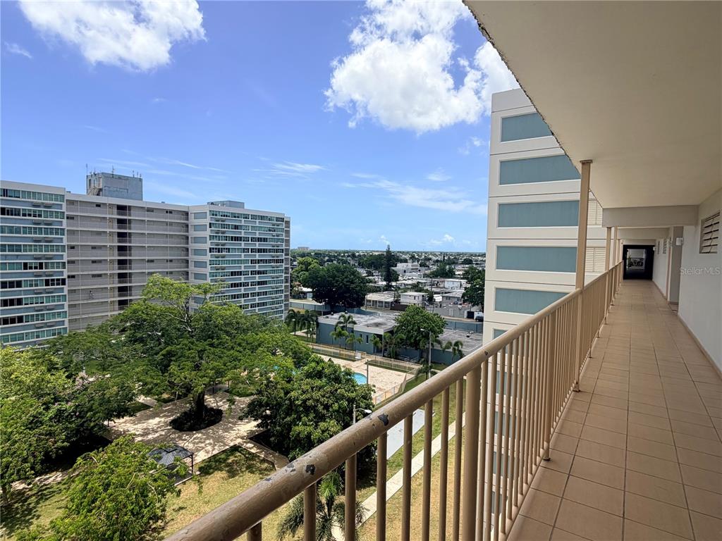 A high-rise balcony overlooks a courtyard with trees, a swimming pool, and neighboring apartment buildings — #850 CALLE EIDER UNIT A808, SAN JUAN, PR