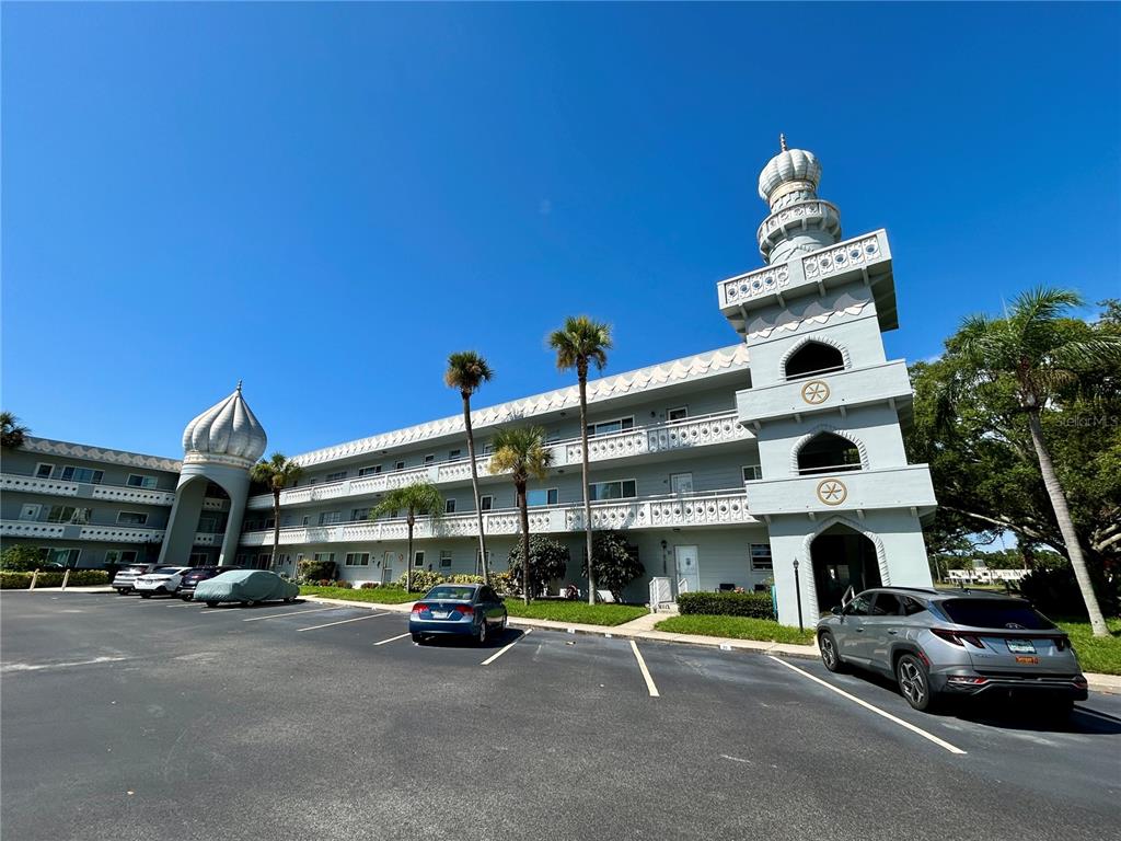 A multi-story apartment building features distinctive onion-shaped domes and a central tower in a parking lot — 2340 GRECIAN WAY UNIT 38, CLEARWATER, FL