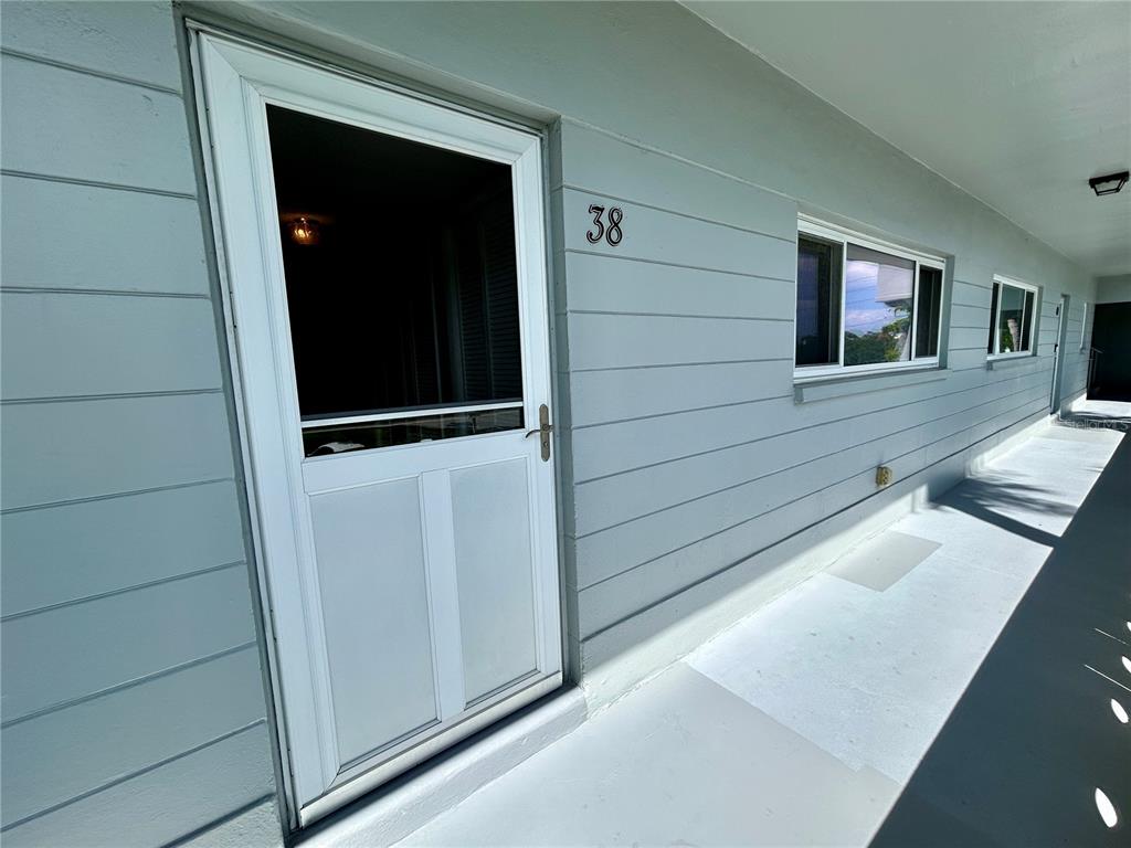 A light blue exterior wall features a white storm door labeled 38 and a window — 2340 GRECIAN WAY UNIT 38, CLEARWATER, FL