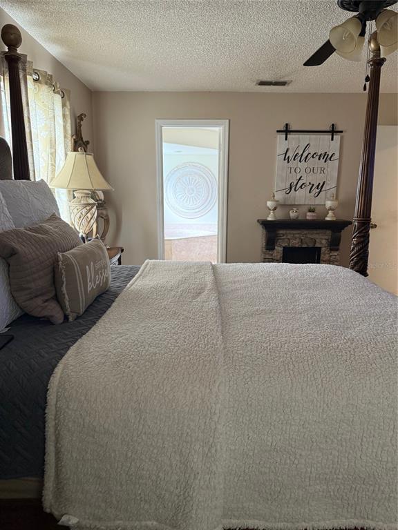 A bedroom features a four-poster bed, a stone fireplace with a sign, and a doorway — 4298 SW 139 STREET ROAD, OCALA, FL