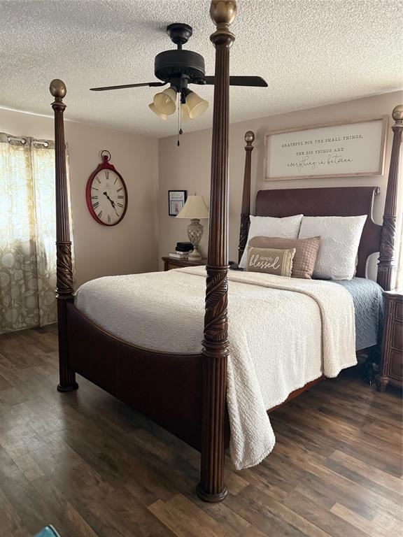 A bedroom features a wooden four-poster bed, wood-look flooring, a ceiling fan, and wall decor — 4298 SW 139 STREET ROAD, OCALA, FL