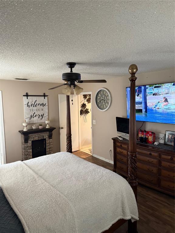 A bedroom features a four-poster bed, a stone fireplace, a ceiling fan, and a television — 4298 SW 139 STREET ROAD, OCALA, FL