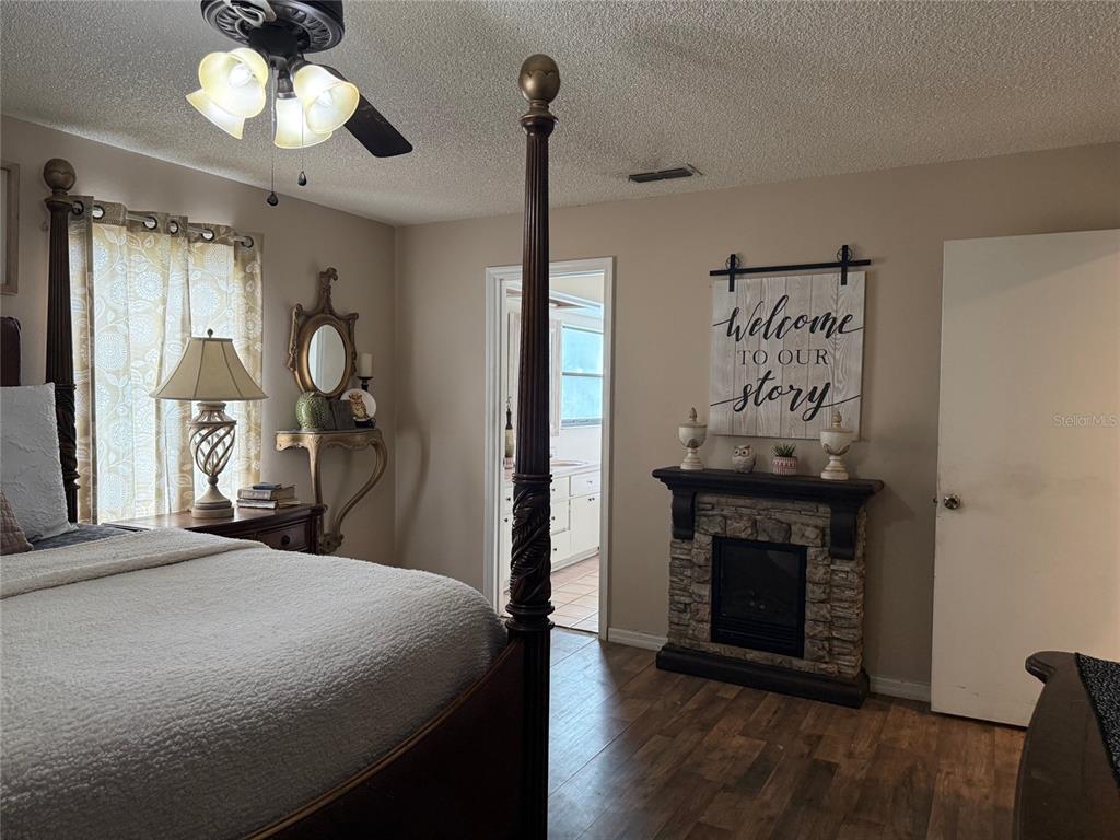 A bedroom features a four-poster bed, a stone fireplace, and a doorway leading to a bathroom — 4298 SW 139 STREET ROAD, OCALA, FL